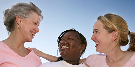 three diverse and multi-generational female women smiling and wearing pink for breast cancer awareness  