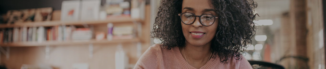 Woman in pink sweater wearing black glasses.