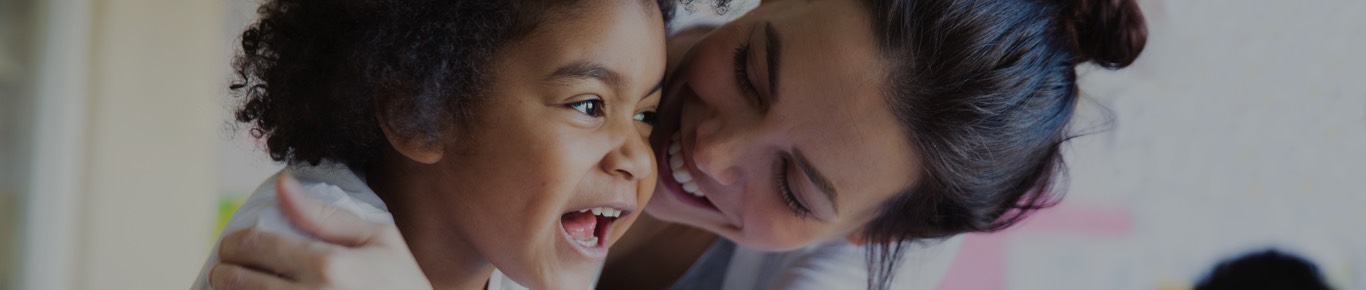 Woman hugging her smiling child from the side.