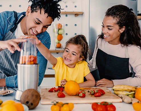 young family making a healthy smoothie in the kitchen