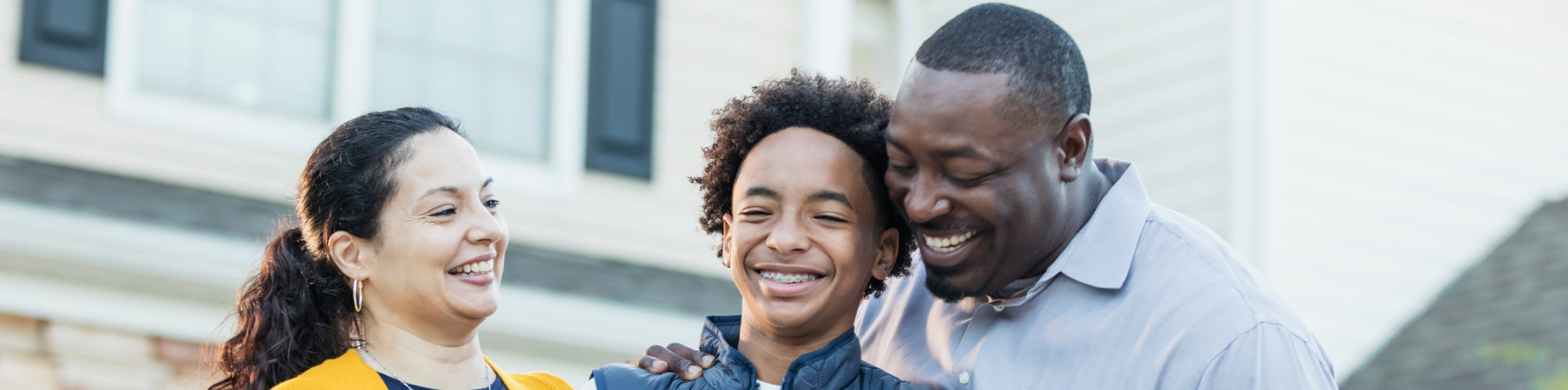 A family of two adults and one child smiling