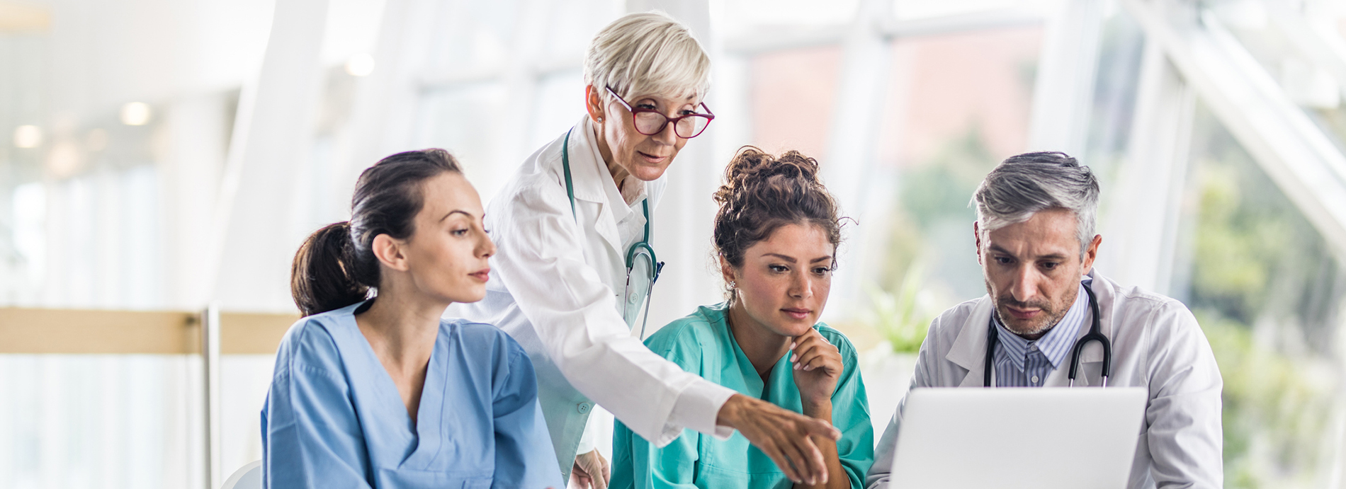 Group of doctors cooperating while reading medical analysis on a computer at doctor's office.